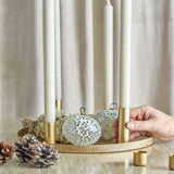 Maxime Iron Christmas Candle Holders Set of 7 in gold, round textured tray with slim tube holders and white taper candles, styled with moss, pinecones and mosaic baubles.