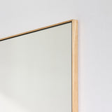 Close-up of the oak frame edge, the pale timber running along the glass with the mitre visible at the corner.