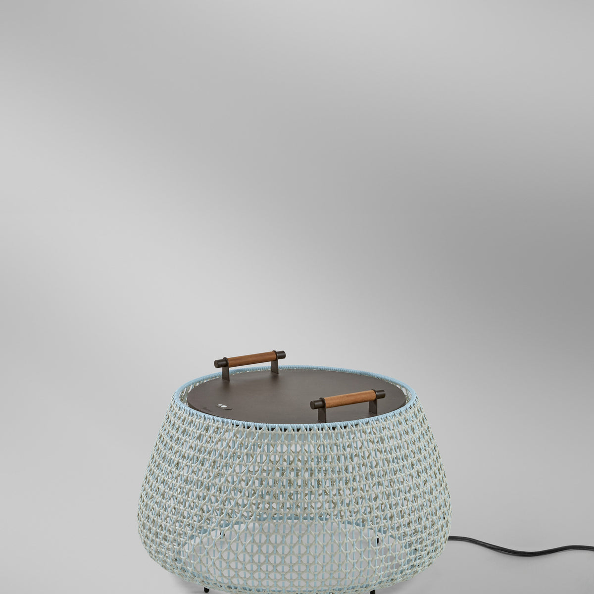 Nans Bag/38 Wood LED outdoor floor lamp with beige open-weave round shade, flat top and teak carry handles, shown on a plain light grey background.