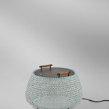 Nans Bag/38 Wood LED outdoor floor lamp with beige open-weave round shade, flat top and teak carry handles, shown on a plain light grey background.