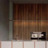 BIMU S200 Ele Linear LED Pendant Light in black with an orange detail, slim floating bar mounted above a wood-panelled kitchen island with integrated under-cabinet lighting.
