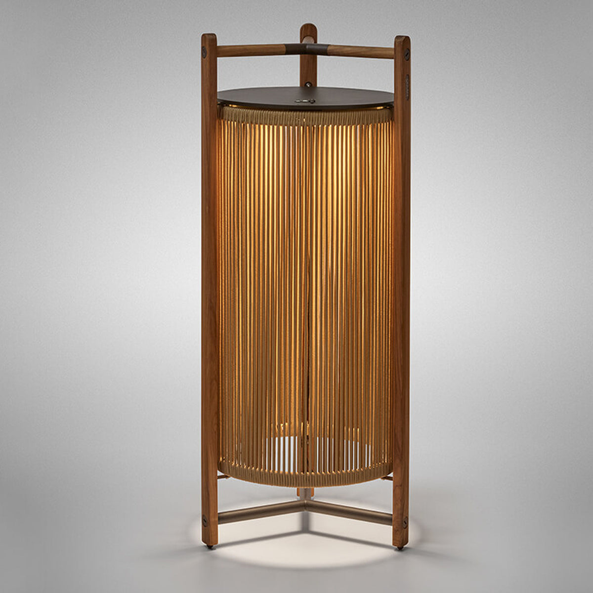 Kando P/111/R rechargeable outdoor floor lamp with sand nautical cord cylinder in a teak wood frame, brown top disc, and three-legged base, lit from within, on a plain light background.