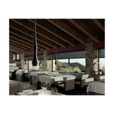 Slend 01 Aluminium Pendant Light in matte black with slim tapering bodies, shown in multiples above a restaurant dining area with stone pillars and timber ceiling beams.