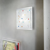 A contemporary art piece adorns the wall, showcasing a white background with vibrant, abstract shapes in shades of red, blue, yellow, and green. Dynamic lighting effects illuminate the artwork. Below it is a segment of another piece featuring geometric patterns in muted tones under the Horizon 3 Light Ceiling & Wall Light - Multicolour.