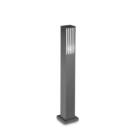 The Moon Outdoor Bollard Light - Grey is a modern, tall lighting fixture featuring vertical slats at the top and crafted from powder-coated aluminum. It stands on a square base against a white background and boasts an IP44 rating for reliable performance in outdoor settings.