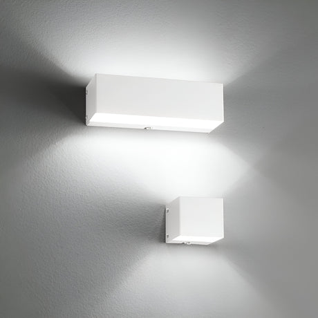 A pair of Vividara 2 Light Wall Lights in white, installed on a gray wall, emit an ambient glow that creates symmetrical patterns of light and shadow, enhancing the modern and minimalist aesthetic.