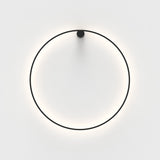 Ramona LED Wall Light in matt black, a thin circular ring with a round top mount, glowing warm white against a plain light background.
