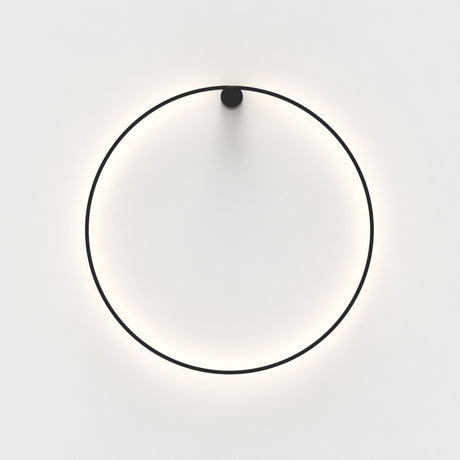 Ramona LED Wall Light in matt black, a thin circular ring with a round top mount, glowing warm white against a plain light background.