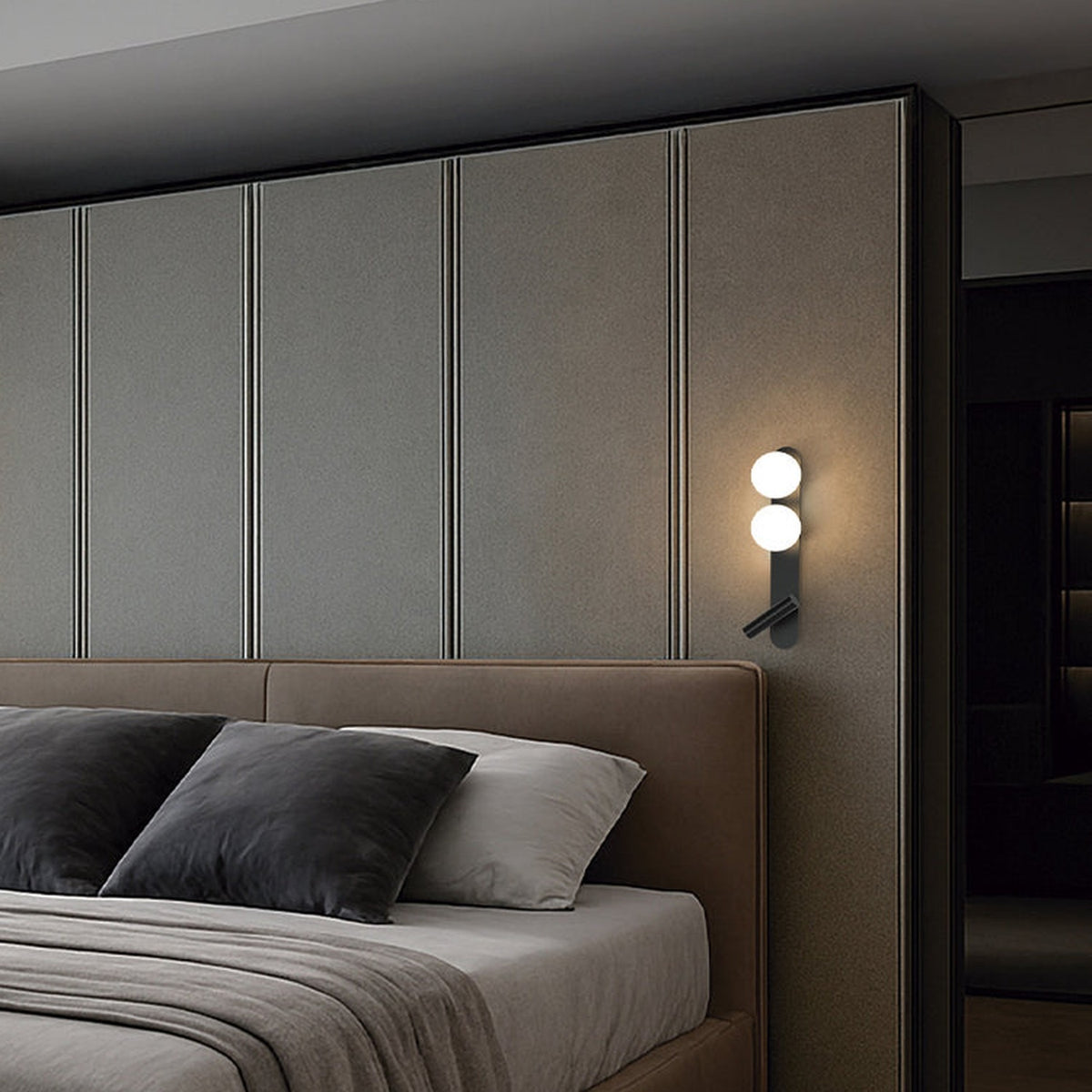 Bubble Opal Globe Wall Light with Reading Light in matt black, two glowing glass globes and angled reading light on a tall backplate, mounted beside a bed with headboard and pillows.