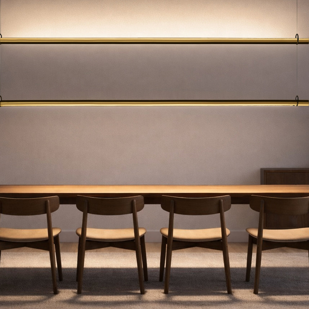 Solid SH Sens 160 cylinder LED pendant lights in brass finish, two slim horizontal tubes mounted above a wooden dining table with chairs in a soft-lit dining room.