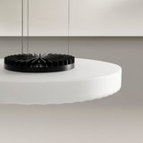 Close-up of the Côte frosted white glass LED pendant light's round disc shade and black finned heat sink, suspended by thin cables against a neutral background.