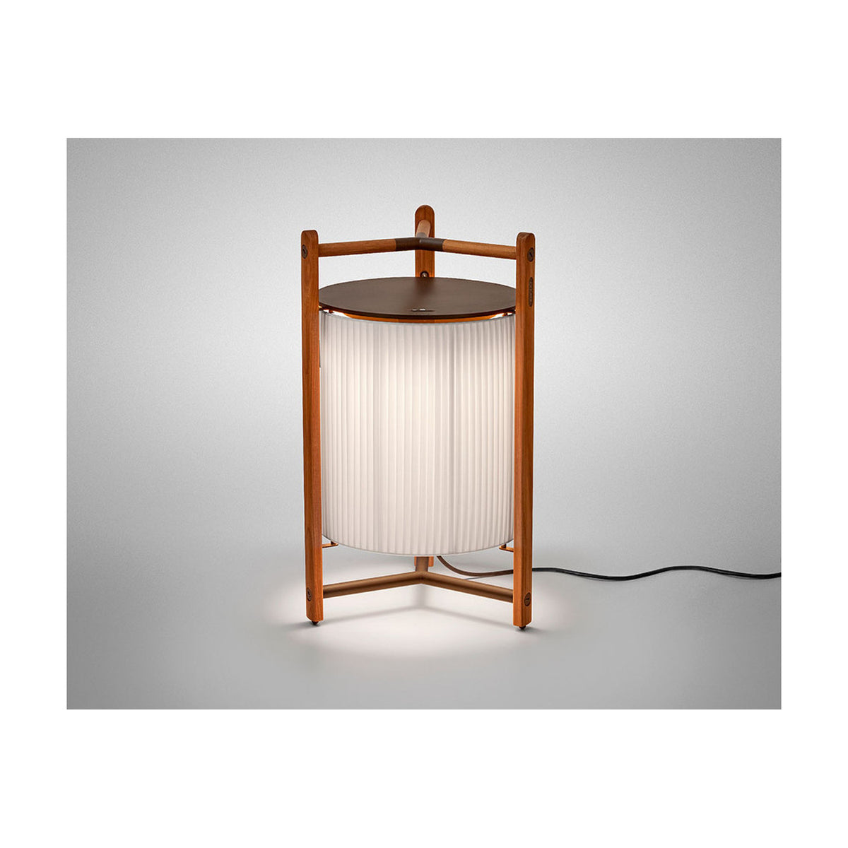 Kando P/76 Ribbon LED floor lamp with a pleated cream translucent cylinder shade, teak wood tripod frame, and round brown top, shown lit on a plain light background.