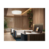 Urban PF/120 Ribbon LED ceiling light with a round white drum shade and integrated warm white LED, illuminating a wood-slatted lounge with white tufted sofas.