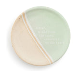 Round ceramic trinket dish in mint green and speckled beige with a diagonal white and beige striped divide, printed "Sister, friend from the start, connected by the heart", on a white background.