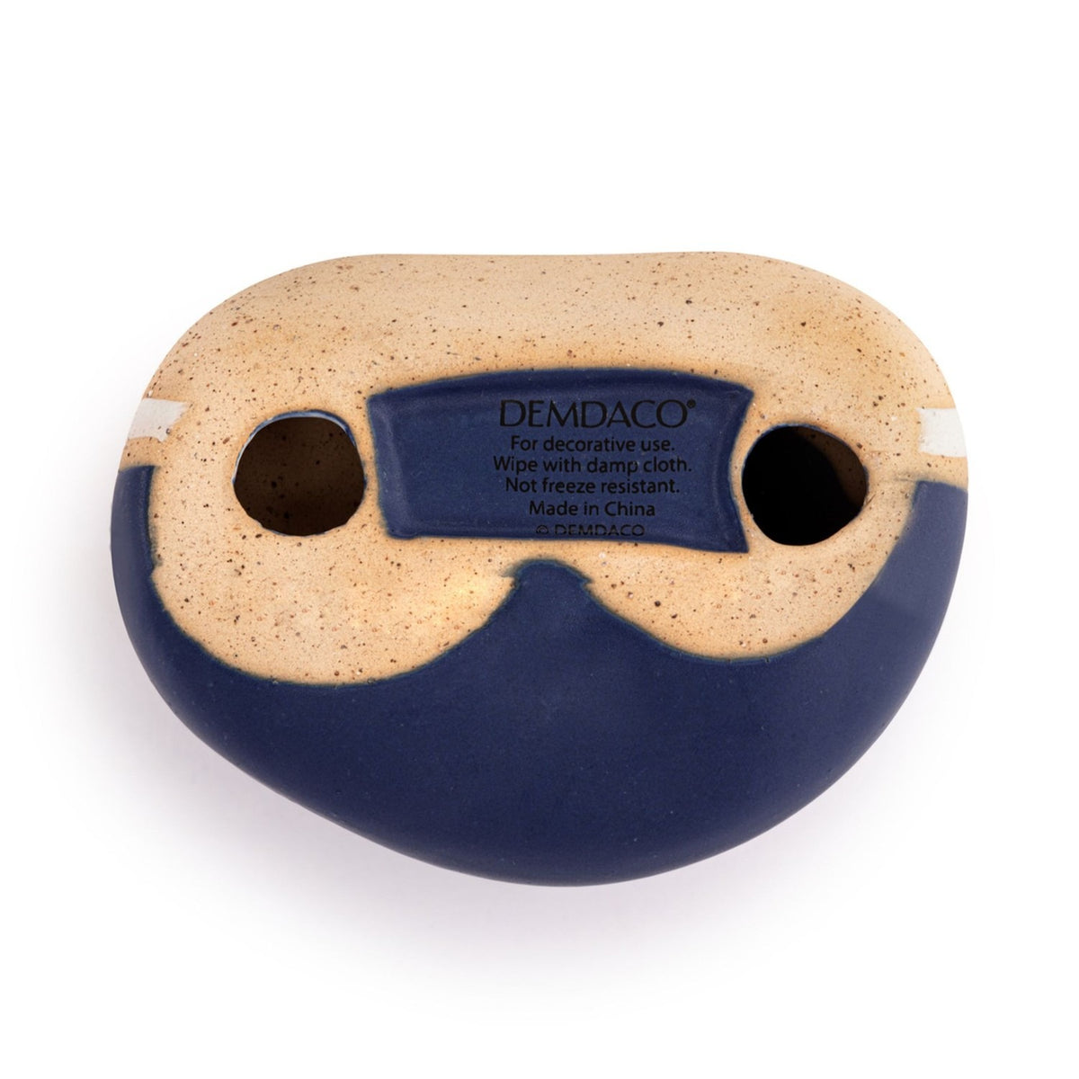 Underside view of the Enjoy the Journey Speckled Ceramic Stone Ornament in blue, showing a sand-speckled base with two eye-like holes and a care label, set against a plain white background.