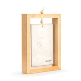 Standing plaque in an open wood frame with a hanging bead cord, holding a stone-coloured ceramic tile embossed with stars and a crescent moon above "love you" text, shown on a plain white background.