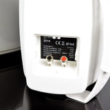 Close-up of the Adastra BH4-W IP44 speaker rear panel showing spring terminal connectors and the white moulded cabinet's specification label.