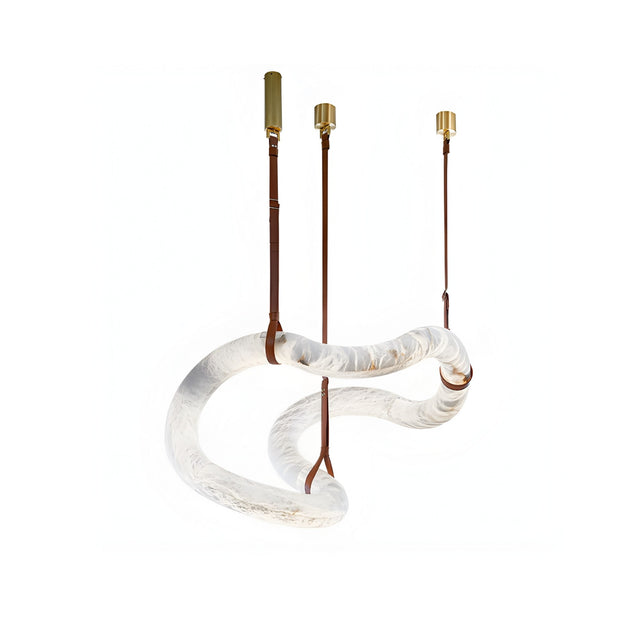 The Serava LED Small Alabaster Asymmetric Suspension Light in Brown & Soft White features a twisted translucent glass tube with brown leather straps and brass fixtures—perfect for luxury bedside lighting against a white background.