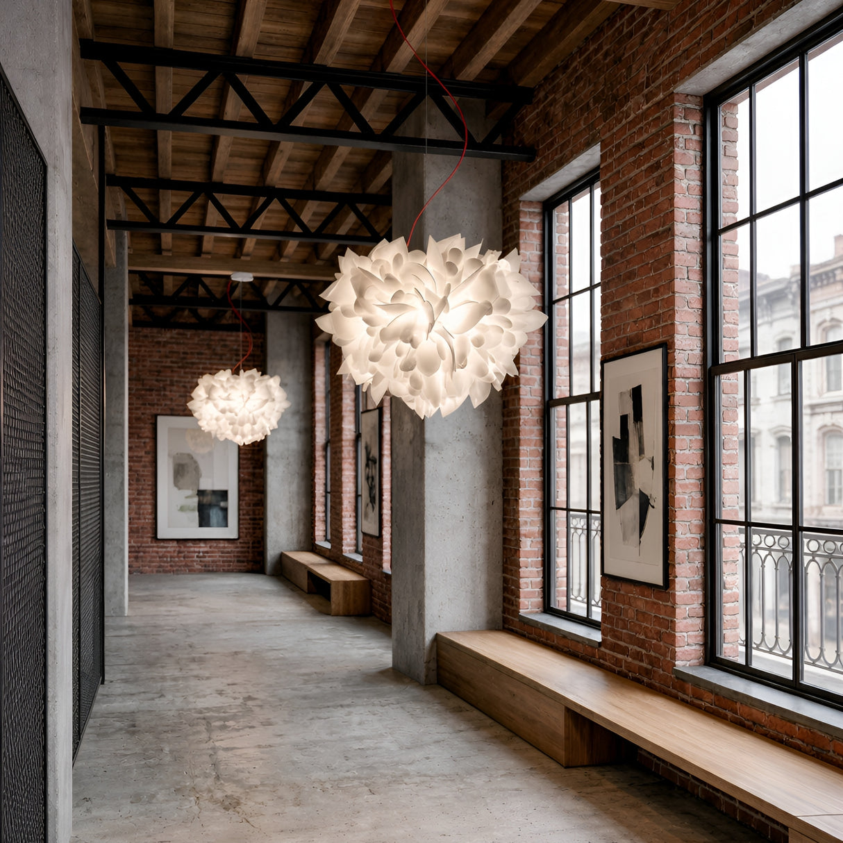 A modern industrial hallway with exposed brick, large windows, wooden benches, and concrete floors features two Violla 2 Light Pendant - White fixtures overhead, while framed abstract art adds character to the space.