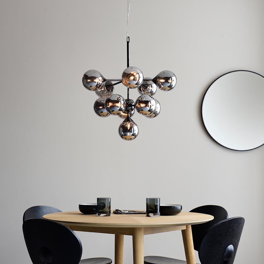 Endon Fitzroy 11 light pendant in chrome and black with smoked mirror glass globes, hanging above a wooden dining table beside a round black wall mirror.