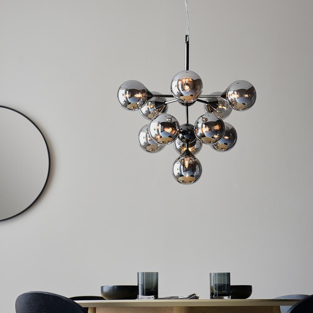Endon Fitzroy 11 light pendant in chrome and black with clustered smoked mirror glass globes, hanging above a dining table beside a round black mirror.