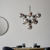 Endon Fitzroy 11 light pendant in chrome and black with clustered smoked mirror glass globes, hanging above a dining table beside a round black mirror.