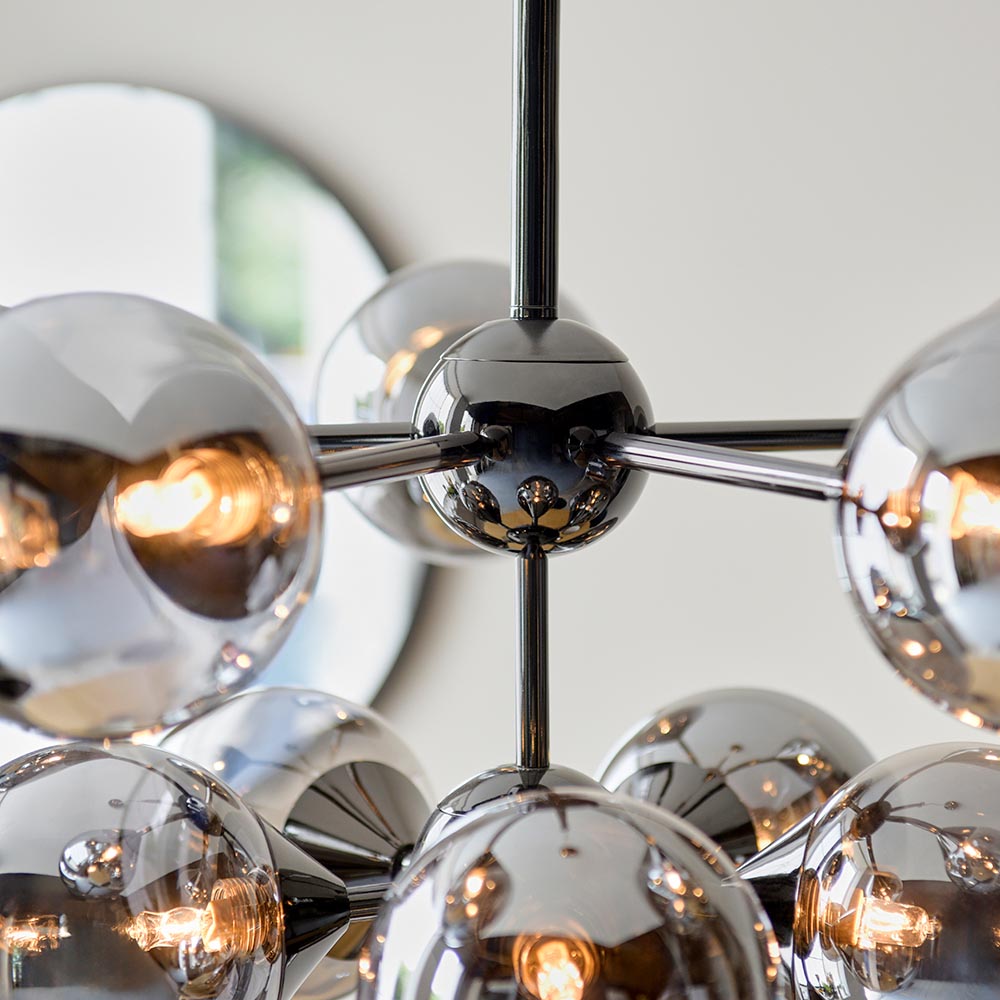 Close-up of Endon Fitzroy 11 Light Pendant in black chrome with smoked mirror glass globes on slim arms, shown near a round wall mirror.