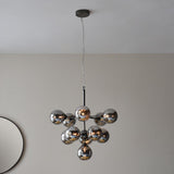 Endon Fitzroy 11 light pendant in black chrome with tiered smoked mirror glass globes, suspended from a ceiling near a round mirror.