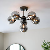 Endon Fitzroy 6 light semi-flush ceiling light in black chrome with smoked glass globes on splayed arms, installed on a white ceiling in a bright room.