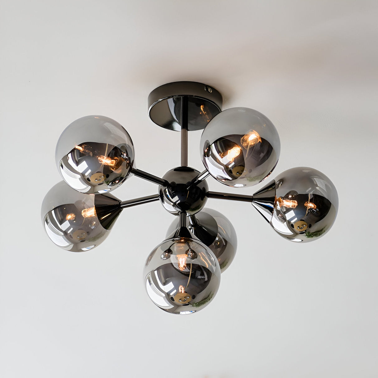 Endon Fitzroy 6 light semi-flush ceiling light in black chrome with six smoked glass globes on angled arms, mounted to a white ceiling.