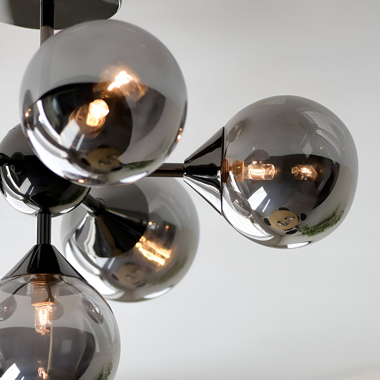 Endon Fitzroy 6 light semi-flush ceiling light in black chrome, close-up of smoked glass globes clustered around brass arms with lit G9 lamps.