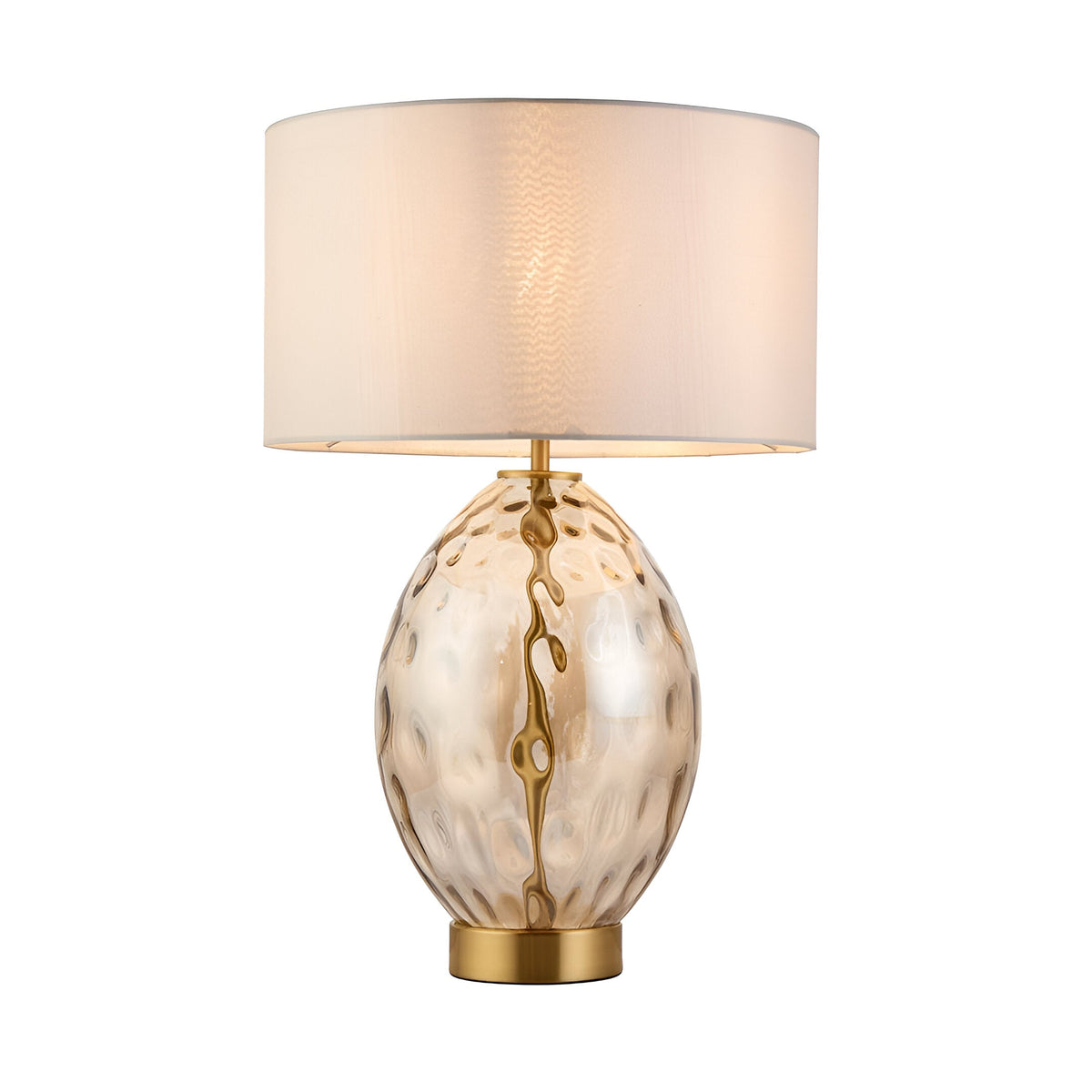 Endon Draycott table lamp with a dimpled amber glass oval base, satin brass fittings and a vintage white fabric drum shade, lit on a white background.