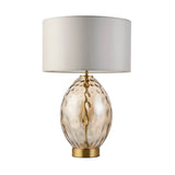 Endon Draycott table lamp with dimpled amber glass ovoid base, satin brass fittings and vintage white fabric drum shade on a plain background.