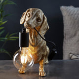 Gold resin dachshund-shaped table lamp holding a black E27 socket with exposed filament bulb in its mouth.
