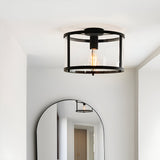 Endon Ellery flush ceiling light in black with a cylindrical glass shade and E27 filament bulb, installed in a hallway above an arched mirror.