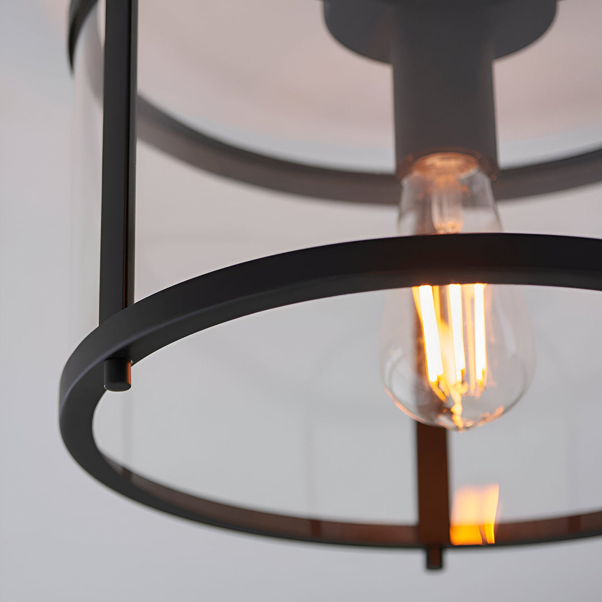 Close-up of the Endon Ellery flush ceiling light in black, showing the circular metal frame and exposed E27 filament bulb.