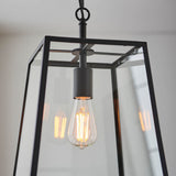 Brenton Lantern Pendant in black, close-up of the box-frame glass shade with an exposed E27 filament bulb hanging from a black rod.