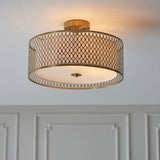 Endon Rosaline 3 light flush ceiling light in gold, drum shade with circular cut-out pattern and diffuser, mounted to a white ceiling above panelling.
