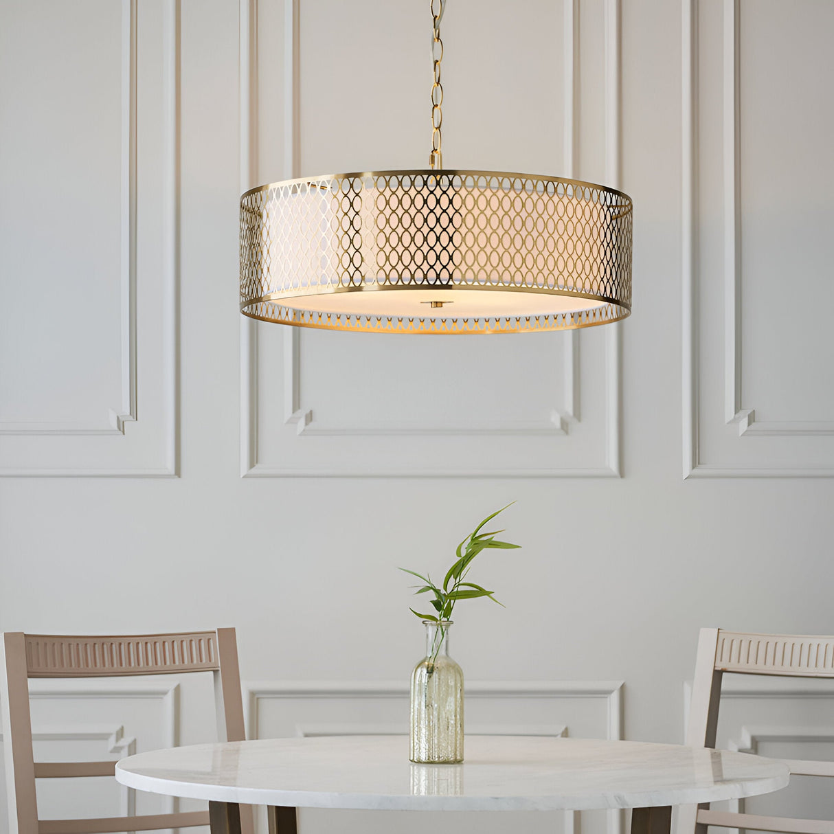 Rosaline 3 Light Pendant in gold with circular fretwork outer and white fabric inner shade, hung above a marble dining table in a panelled room.