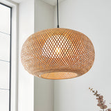 Endon Aldstead globe pendant in natural woven rattan with matt black flex, lit by a warm bulb in a bright white corner beside a window.