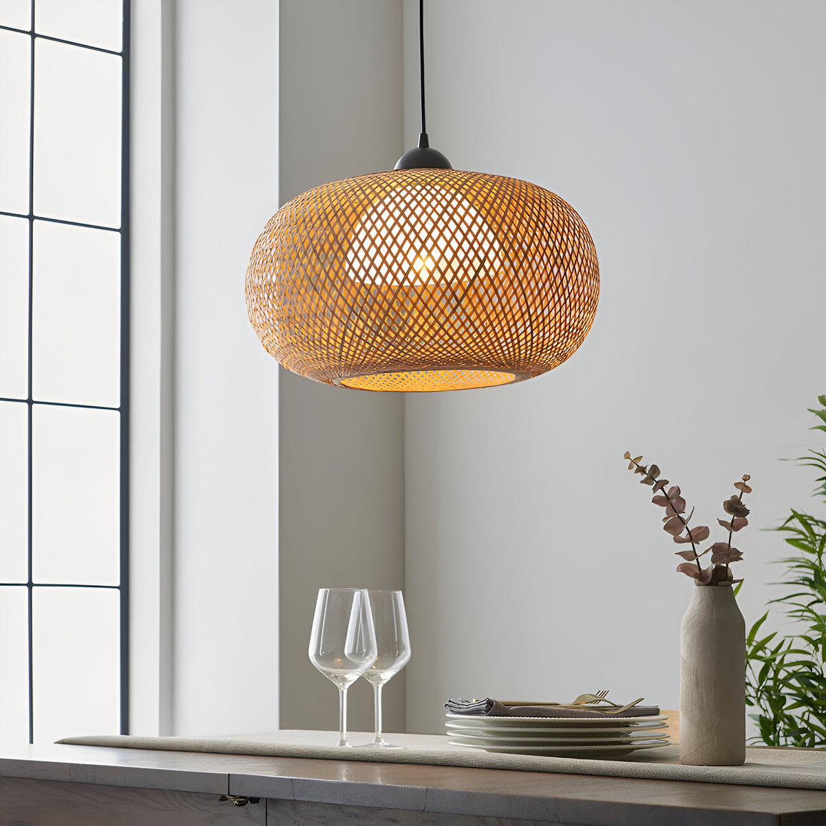 Endon Aldstead woven rattan globe pendant light in natural with matt black ceiling fitting, hung above a dining sideboard beside a bright window.
