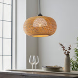 Endon Aldstead woven rattan globe pendant light in natural with matt black ceiling fitting, hung above a dining sideboard beside a bright window.