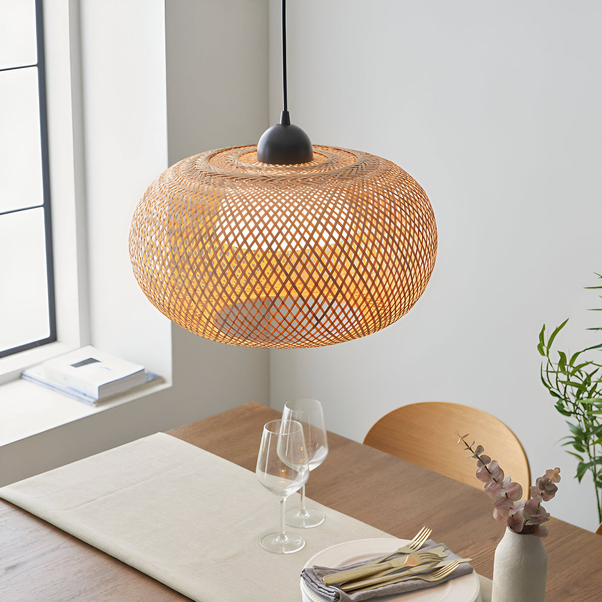 Endon Aldstead globe pendant in natural woven rattan with matt black ceiling fitting, illuminated above a wooden dining table by a bright window.