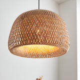 Aldstead Oval Pendant in natural woven rattan with a domed shade and warm interior glow, shown against a white wall in a bright room.