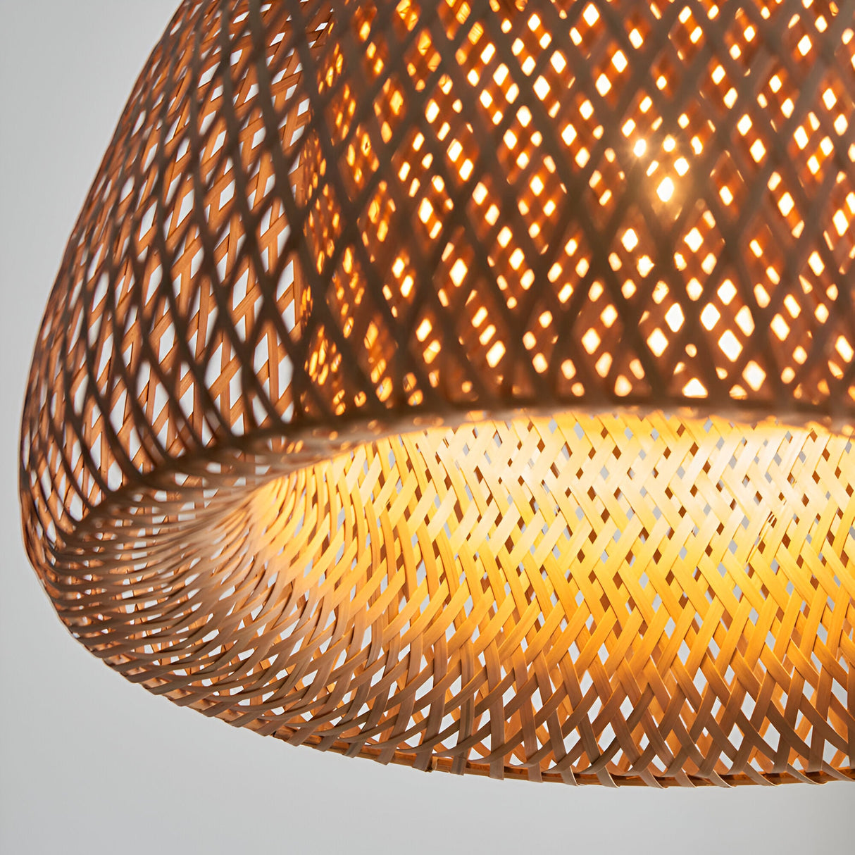 Close-up of the Aldstead Oval Pendant in natural rattan weave with white inner diffuser, showing E27 bulb glow through diamond-patterned openings.