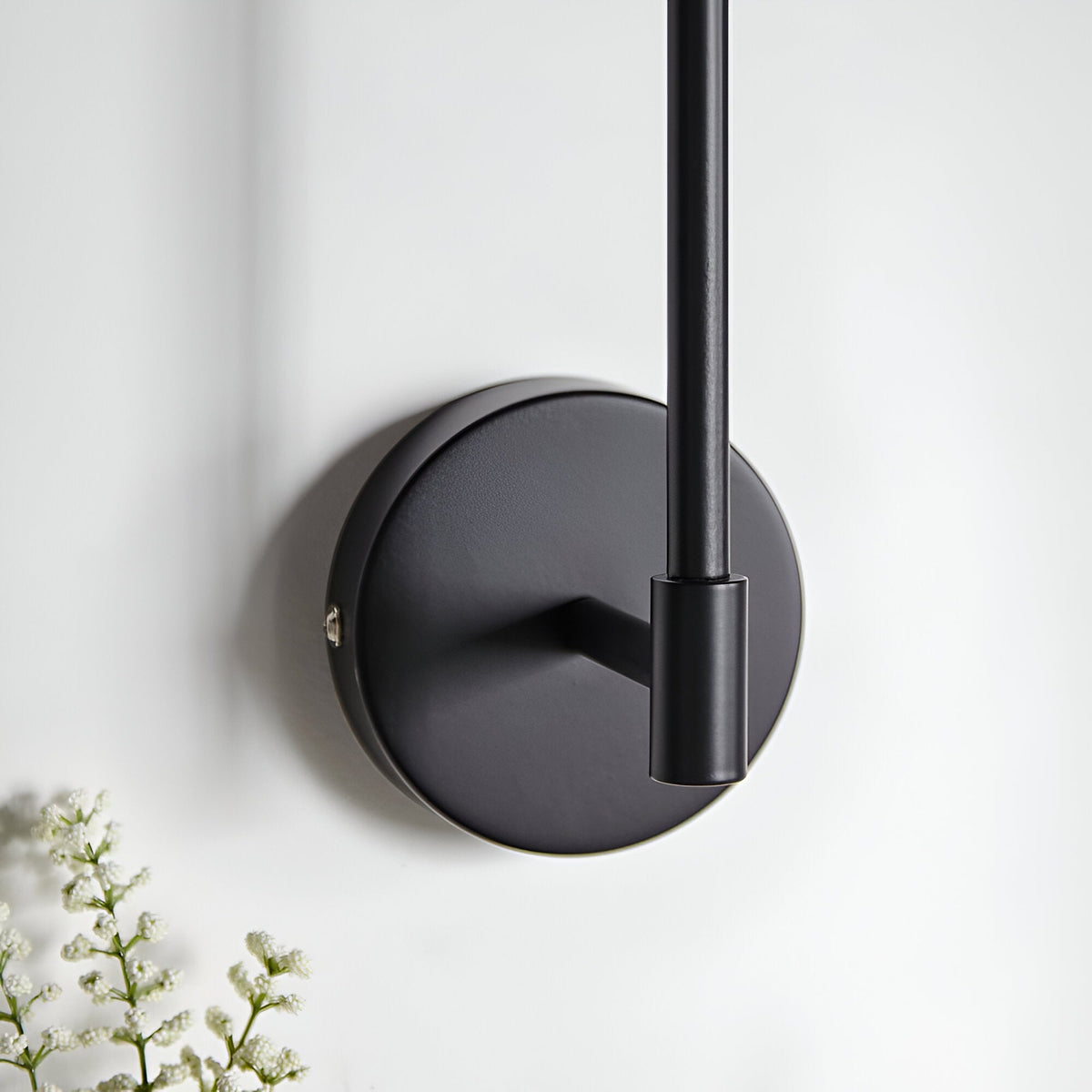 Endon Cliffhurst wall light mounting detail showing the matt black circular backplate and slim upright rod against a white wall.