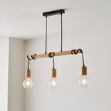 Cranbury 3 Light Linear Pendant in black and natural wood, with exposed bulbs hanging from a slim horizontal bar, shown against a light ceiling and wall.
