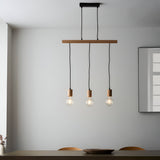 Cranbury 3 Light Linear Pendant in black and natural wood, hung above a dining table with exposed filament bulbs, set against a plain white wall.