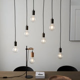 Endon Cliffwell 6 light linear pendant with exposed filament bulbs on black flexes, shown above a dining table with a matching wood and metal desk lamp.