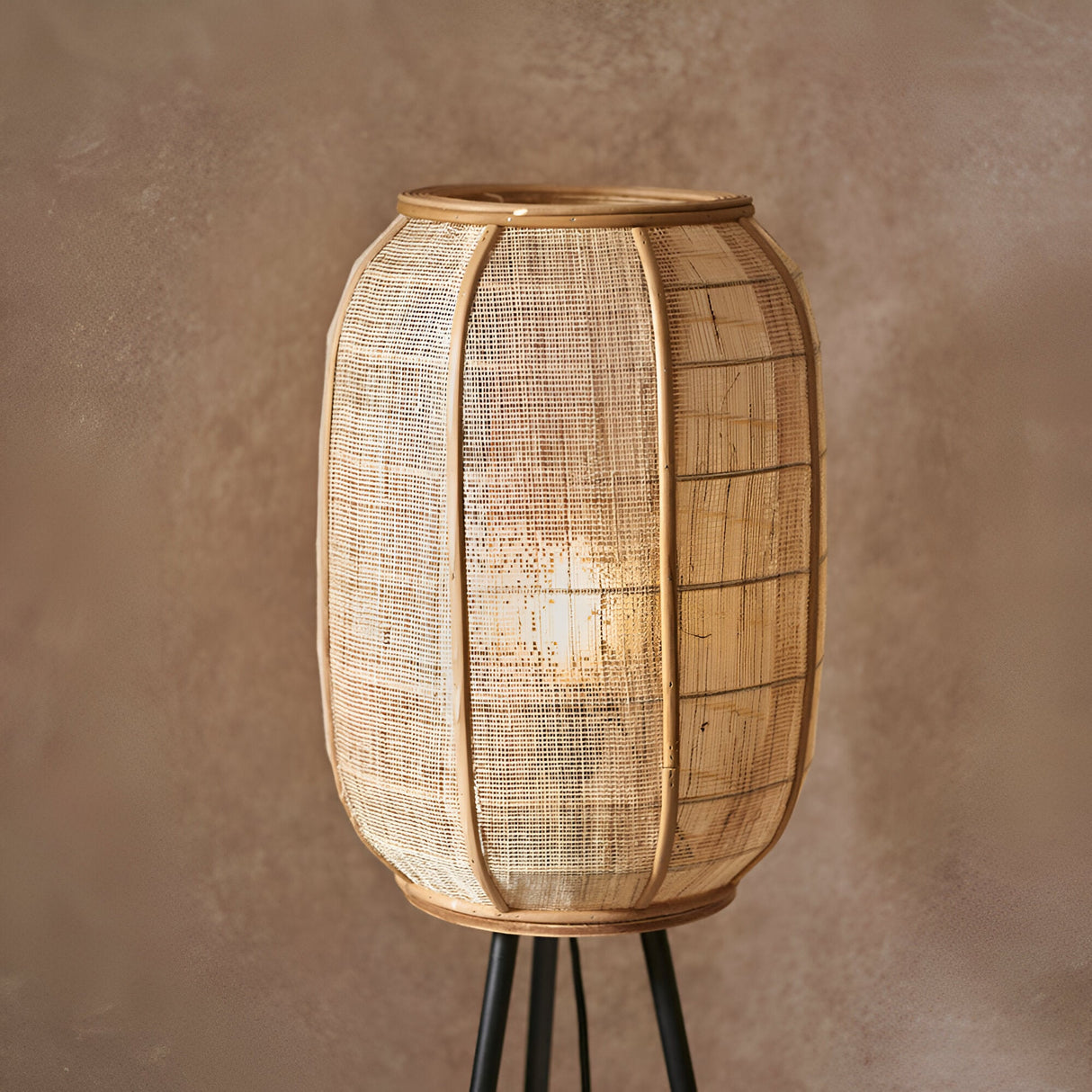 Daneshaw Floor Lamp with cylindrical natural linen and bamboo shade on a matt black tripod base, shown lit against a neutral background.